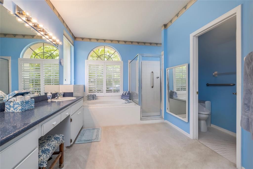 Primary bathroom with garden tub and walk in shower.  Love the plantation shutters.