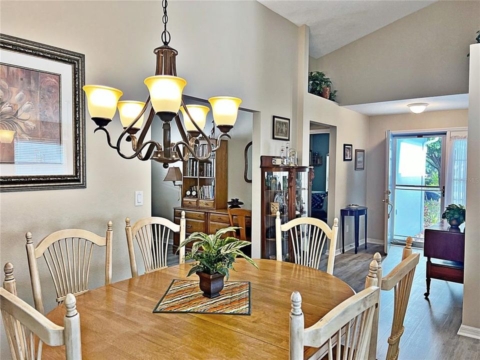 View of living room, vaulted ceilings, and stackable glass doors that lead onto the covered and screened in lanai with partial view of the kitchen