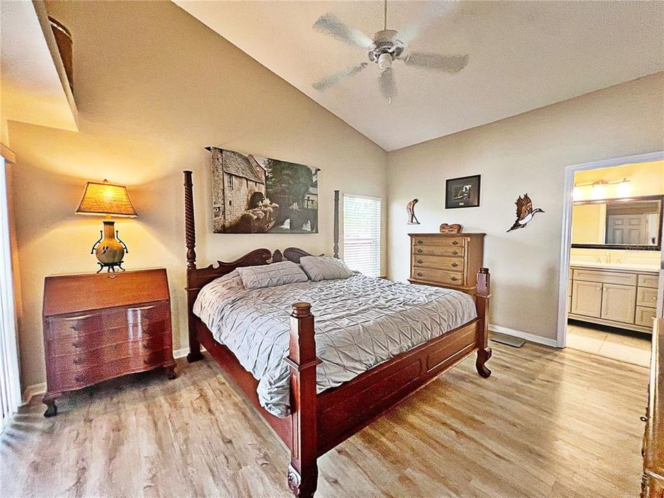 View from master bedroom entry of bedroom with vaulted ceilings and en suite bathroom that features a walk-in closet