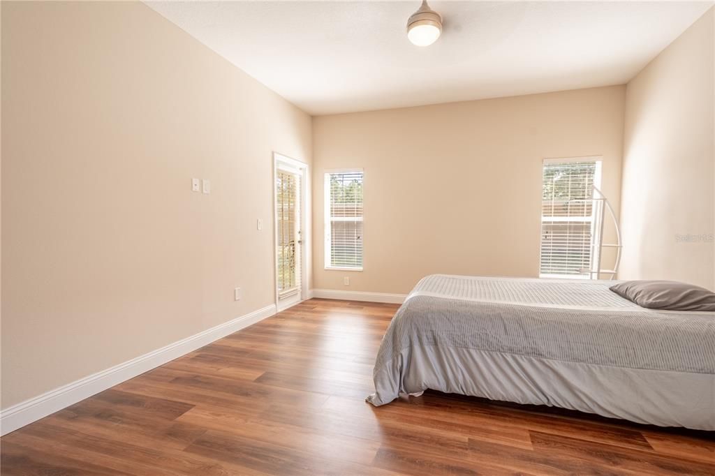 The primary bedroom features a ceiling fan with light kit and French door leading to the screened in porch.