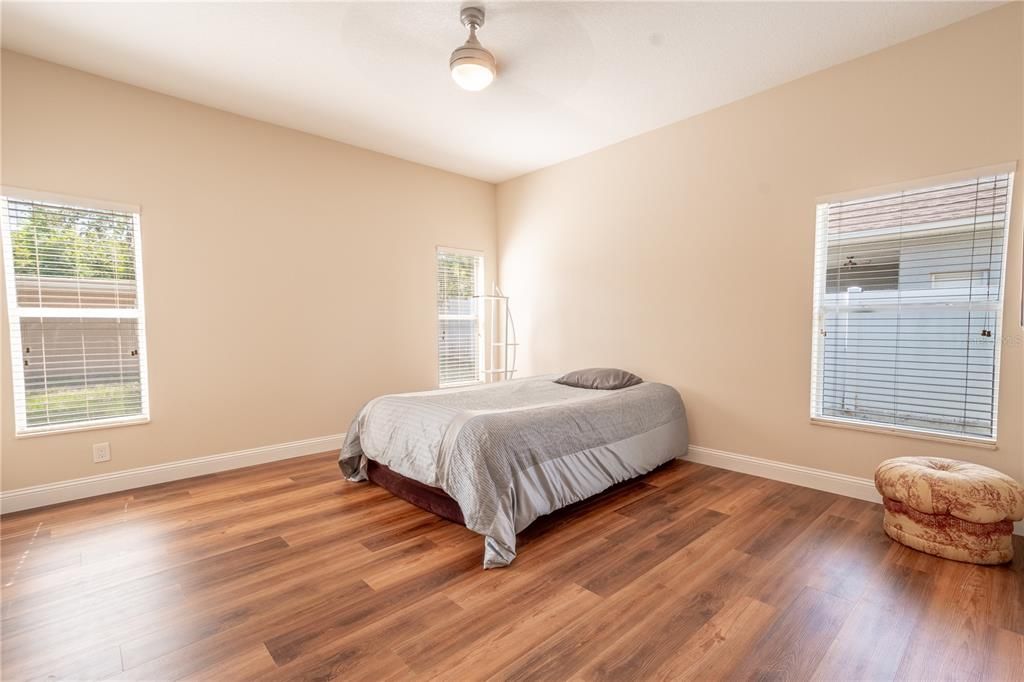 The primary bedroom features wood laminate flooring complimented by neutral tones.