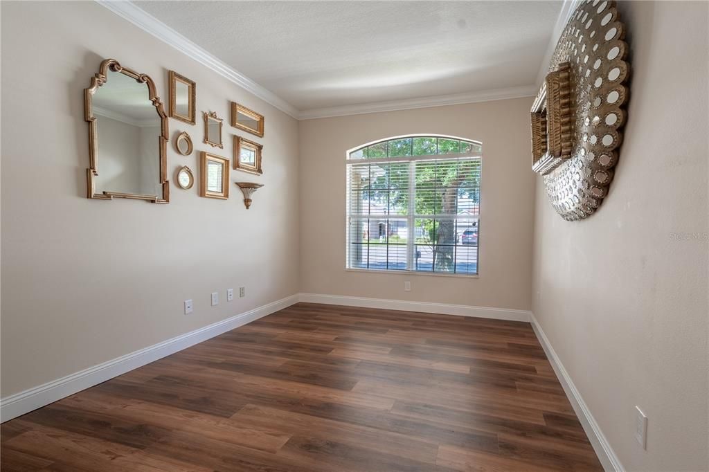 The Living room features rich wood laminate flooring, neutral color palette and a picture window framing the majestic oak.