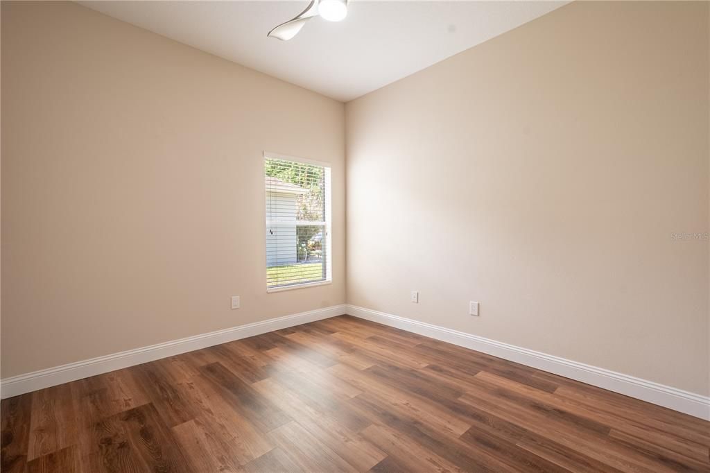 The 2nd bedroom features wood laminate flooring, a ceiling fan, built-in closet and neutral tones.