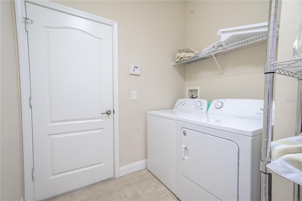 Laundry room features ceramic tile floor, washer/dryer and shelving