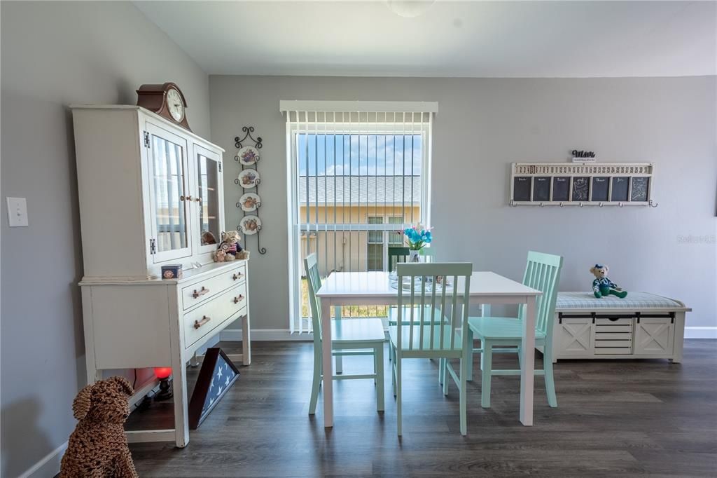 The dining room features a neutral color palette and vinyl wood flooring.