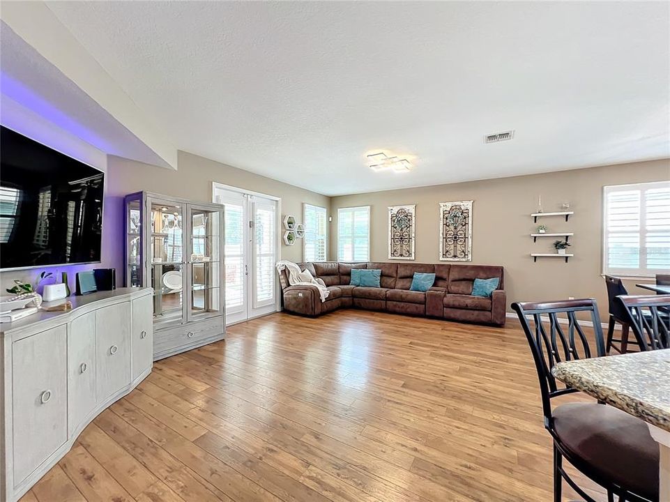 The generous Living room with engineered hardwood floors and French doors leading to the covered lanai and pool area.