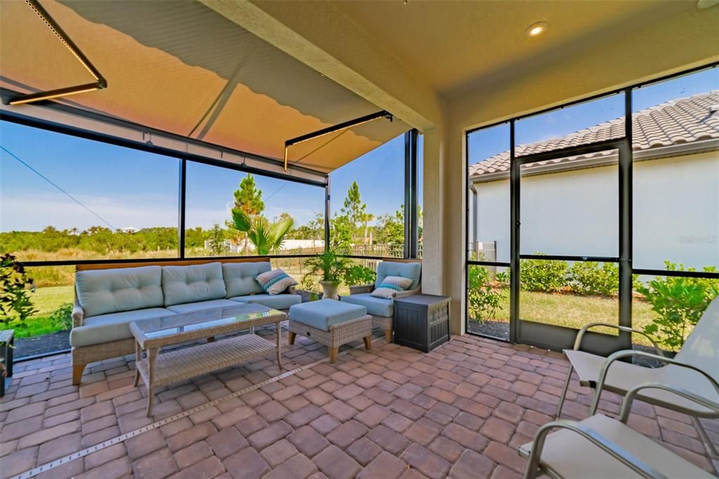 Spacious lanai with brick pavers and automated awning/uv screen to dampen the sun's strength