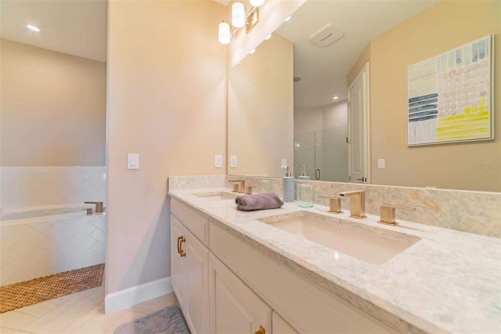 Primary bath with dual sinks, quartz countertops, and upgraded gold tone fixtures