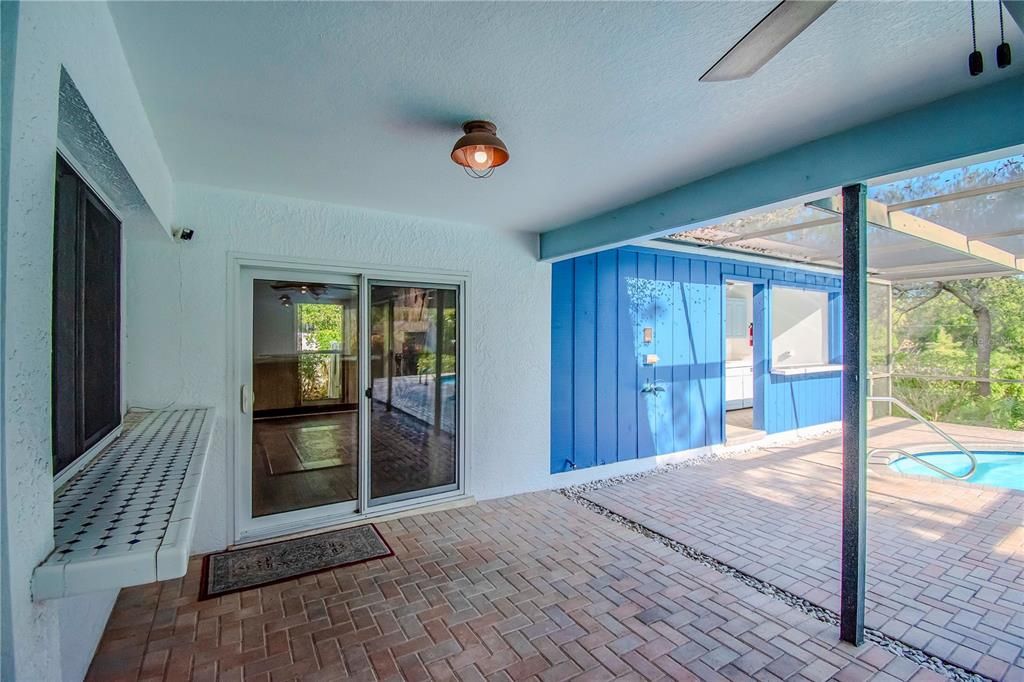 Screened in Pool with Pavers and View of Outdoor Kitchen and Lush Landscaping