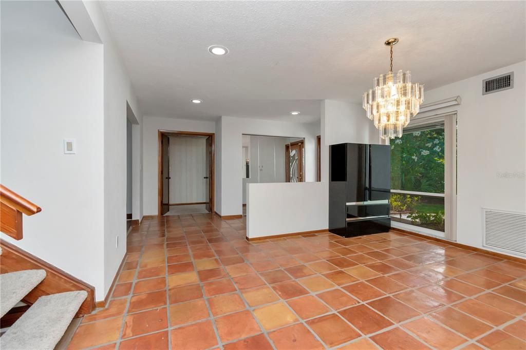 Formal Dining Room with New Paint, Hurricane-Rated Window and Tile Floor. View of Entrance to Stairs, Foyer, Entryway and Double Door Entrance to Primary Suite