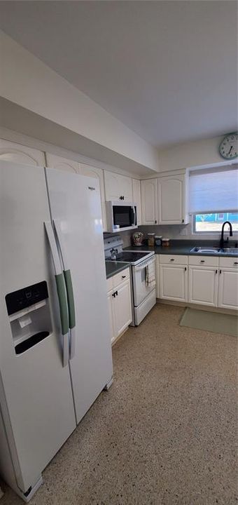 The kitchen features freshly painted cabinets and new black hardware, faucet and new dishwasher