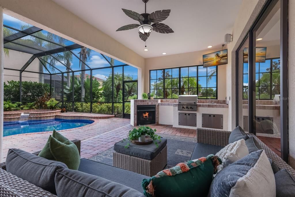 Fabulous covered lanai and outdoor kitchen space with fireplace, TV, grill and sink