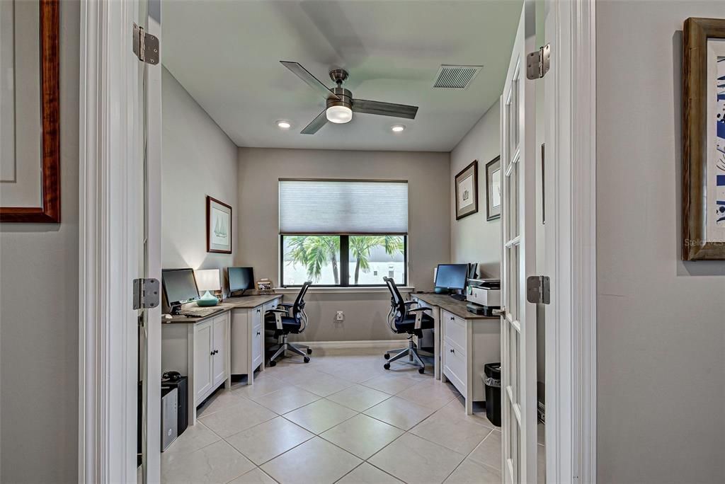 Office with diagonal flooring, added lighting and ceiling fan.