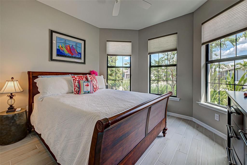 Guest bedroom with angled front wall, fan and lovely plank ceramic flooring.