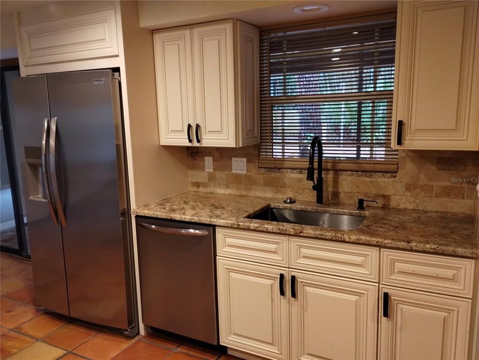 Custom kitchen includes a brand new fridge, wood cabinets, a tumbled marble backsplash and incredible looking granite counters!