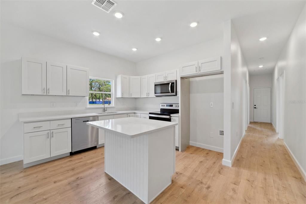 The kitchen delivers a comfortable layout, STAINLESS STEEL APPLIANCES, shaker style cabinetry, an ISLAND with breakfast bar seating and a beadboard accent, solid surface counters and a WALK-IN PANTRY for plenty of storage.