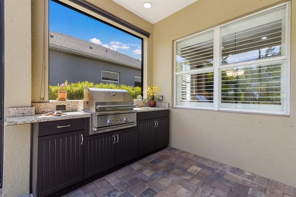 Summer kitchen with built in grill, exterior-grade cabinetry, granite countertops and sun shade