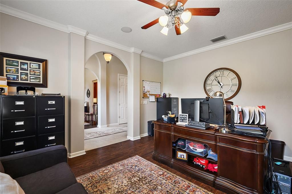 Crown molding, arched doorway and gleaming wood laminate flooring