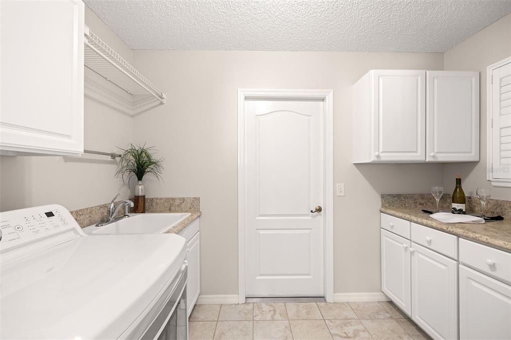 Interior laundry facilities include plenty of cabinet space for storage and utility sink.