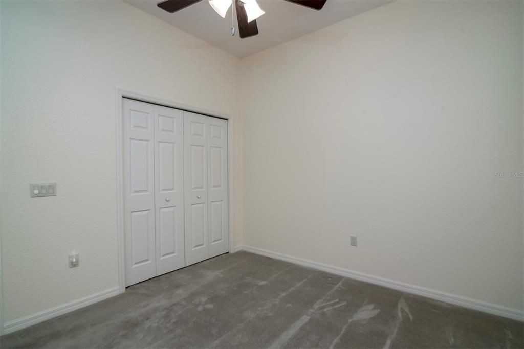 The third bedroom has custom carpeting, ceiling fan with light, and a reach in closet.