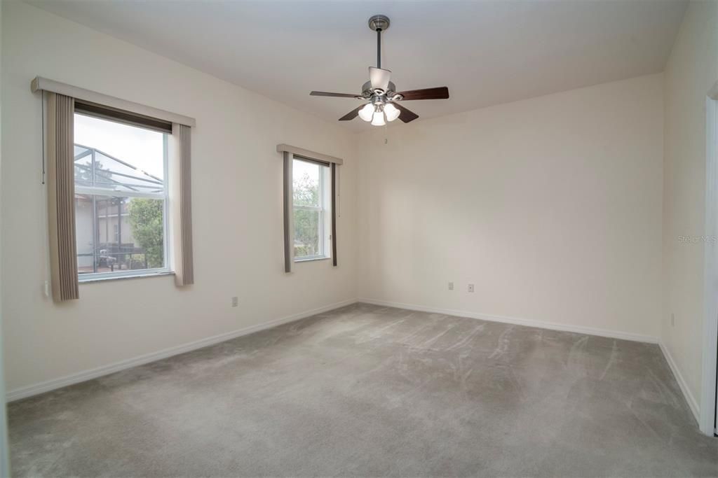 The large primary bedroom has split windows, ceiling fan with light, and custom carpeting.