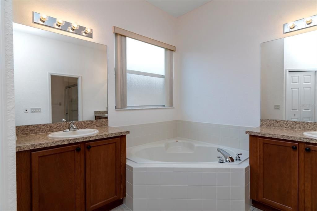 The master bath has 2 elevated wood vanities and a corner garden tub.