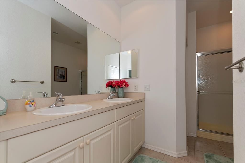 Dual sink vanity, dual walk-in closets, shower, linen closet, and tucked away commode area