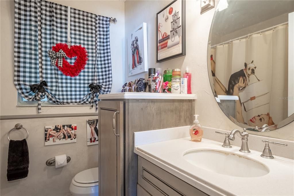 Bathroom 1 features ceramic tile flooring, a mirrored vanity with additional storage and a tub with shower.