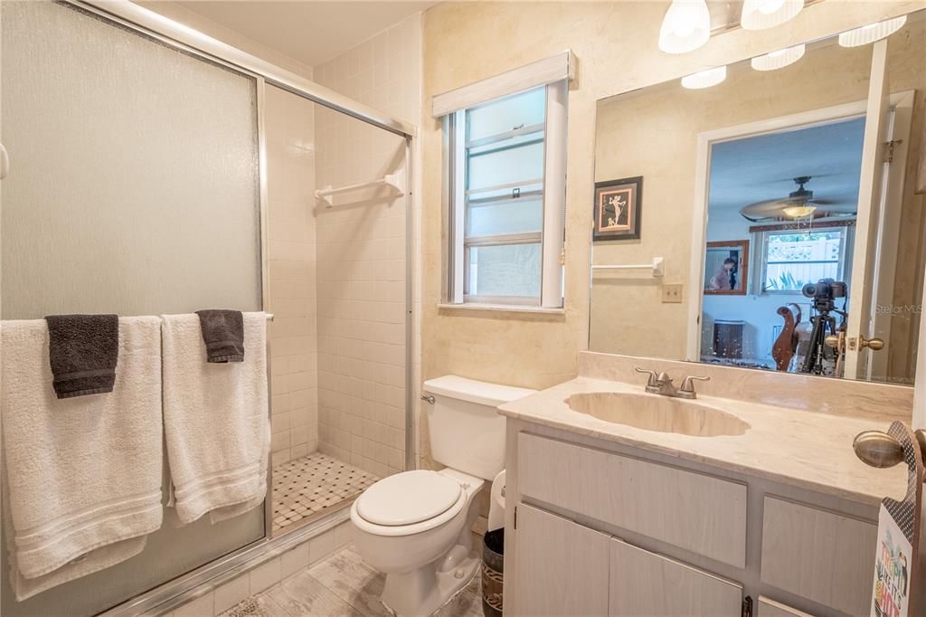 The inlaw/guest room ensuite bath features ceramic tile flooring, a walk in shower and a mirrored vanity with storage and a down light fixture.