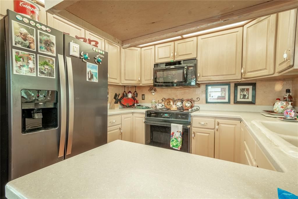 The kitchen features a stainless steel French door refrigerator with ice maker and water dispenser, a range and a microwave.