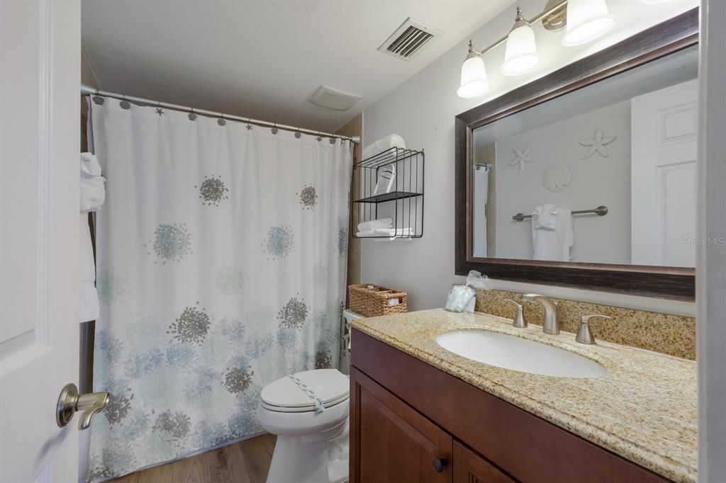 primary en-suite bathroom with tub/shower combo and granite counters