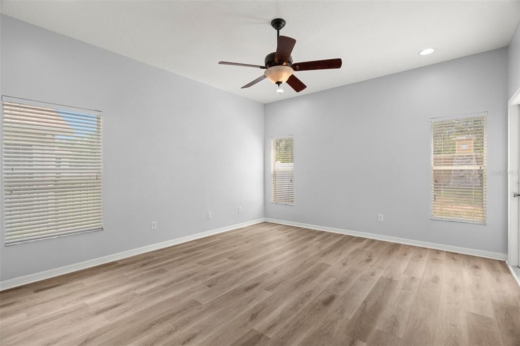 Master bedroom is on the back of the home in this split bedroom plan house and features a ceiling fan/light en suite bath, door to the back covered patio and recessed light.