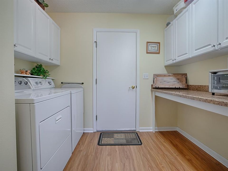 SPACIOUS LAUNDRY ROOM WITH SHELVING AND CABINETS FOR STORAGE