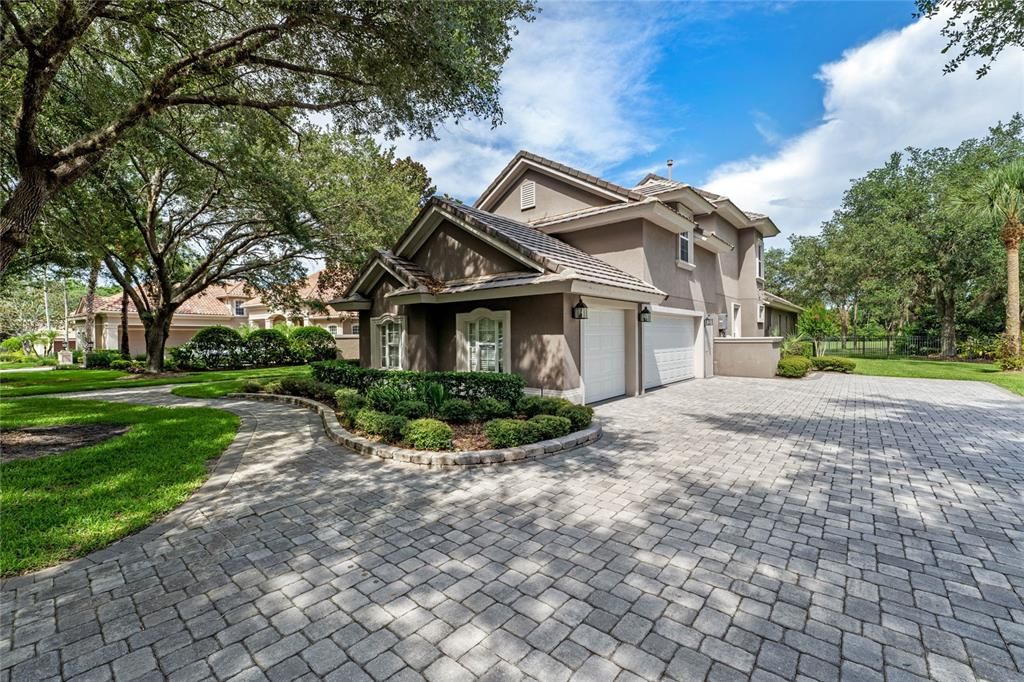 The expansive paver driveway leads to a three-car garage, providing ample parking and a grand entrance to this luxurious residence.