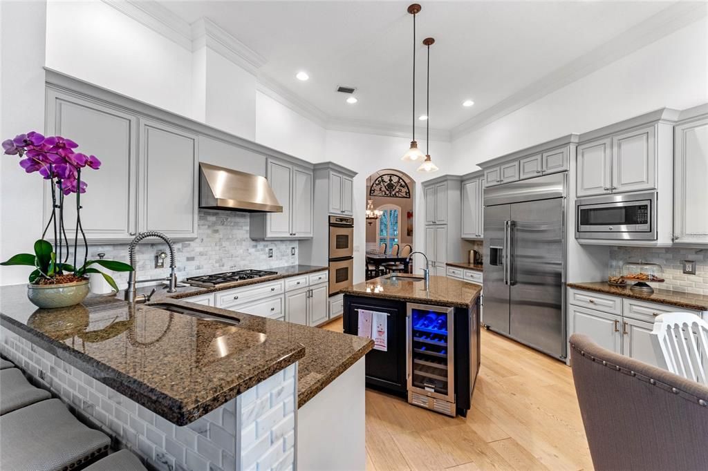 The gourmet kitchen is a chef's delight, boasting granite countertops, stainless steel appliances, and a large center island with a built-in wine chiller.
