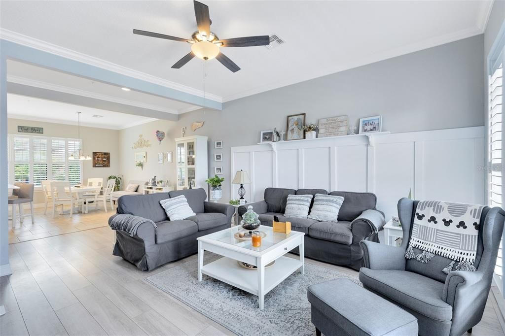 Family/Living Room looking towards the dining room.  Wide Open concept design featuring luxury vinyl flooring, plantation shutters and crown molding.