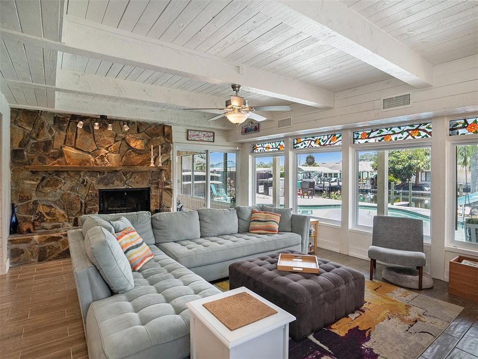 Family room with beamed ceiling, fireplace, and tons of natural light showcasing the pool and canal. with a wet bar keeps the fun going.