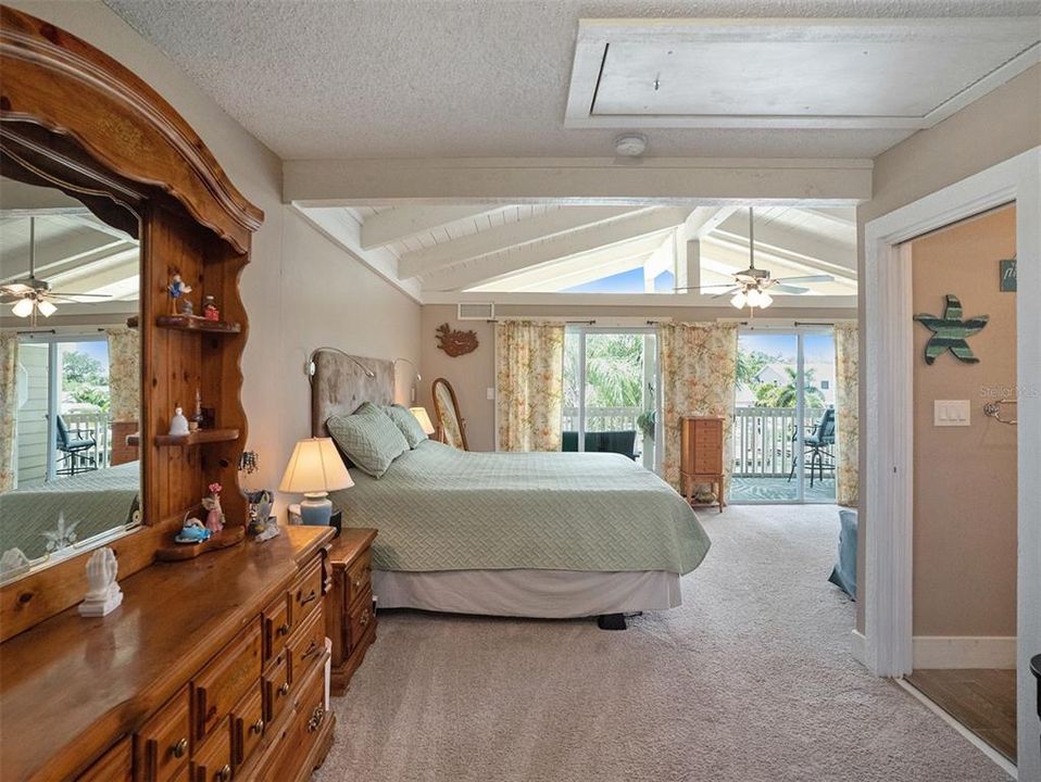 The master suite is adorned with a cathedral ceiling and glass doors opening to a private balcony overlooking the pool and canal.