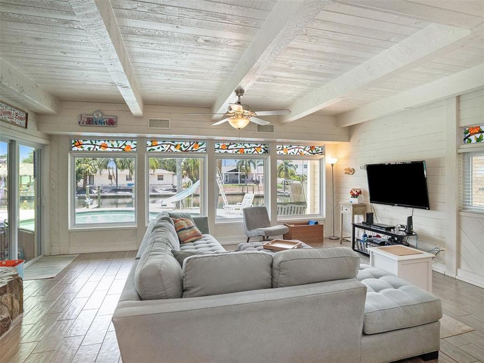 Family room with beamed ceiling, fireplace, and tons of natural light showcasing the pool and canal. with a wet bar keeps the fun going.