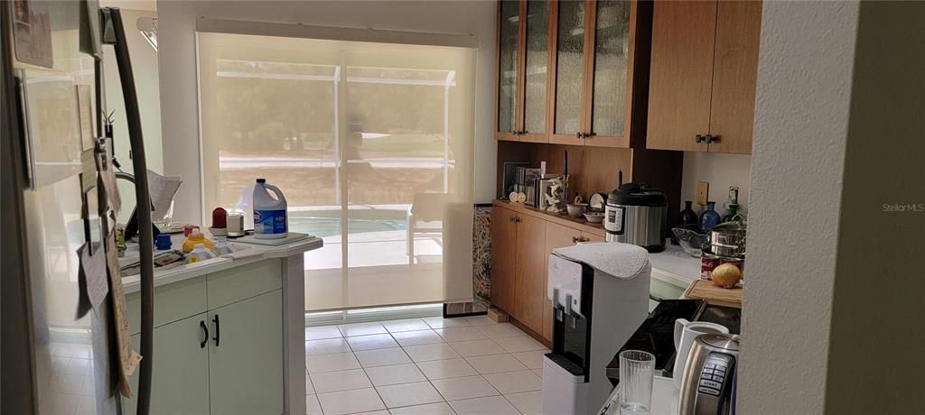 Kitchen opens to the large overed lanai and pool/cage