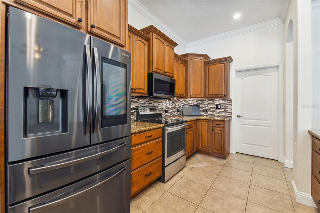 Newer appliances with the door leading to the large laundry room and garage area.