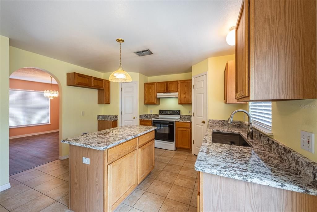The kitchen is filled with modern amenities like granite countertops, a kitchen island for meal prep and additional storage, and 2 walk-in pantries flanking the range for an abundance of storage.