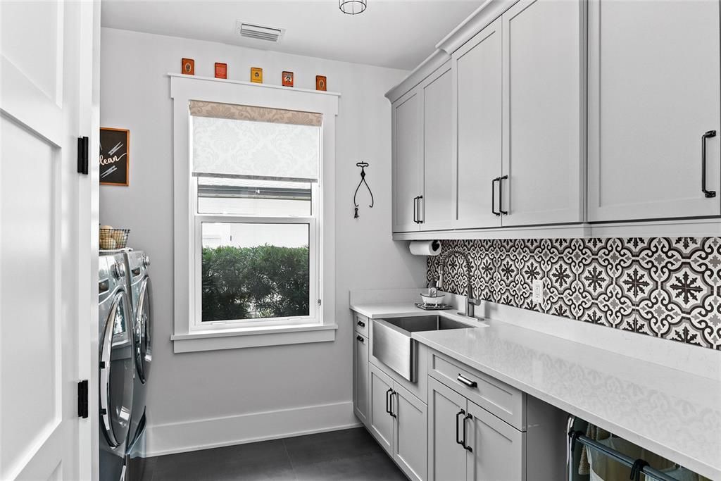 The large laundry room offers tons of cabinets, a sink and large storage closet