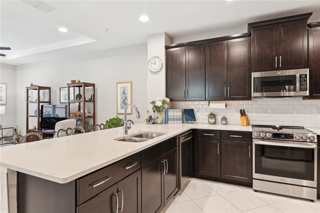 Kitchen with double sink, continued marble flooring and subway tile backsplash.