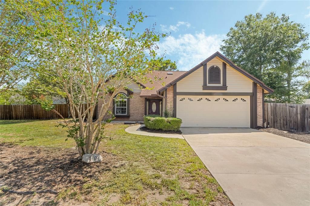 The home has a large driveway and wood fence surrounding the yard.