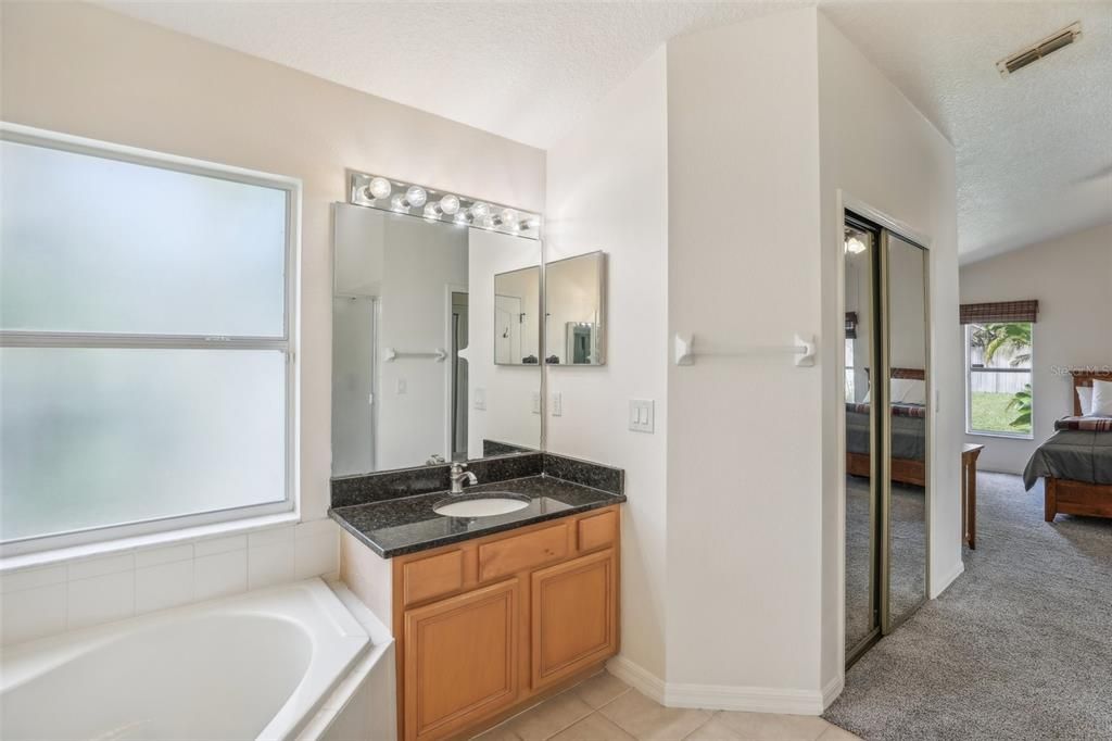 Double Vanity in Primary Bathroom with Garden Tub and Separate Shower and vaulted ceilings