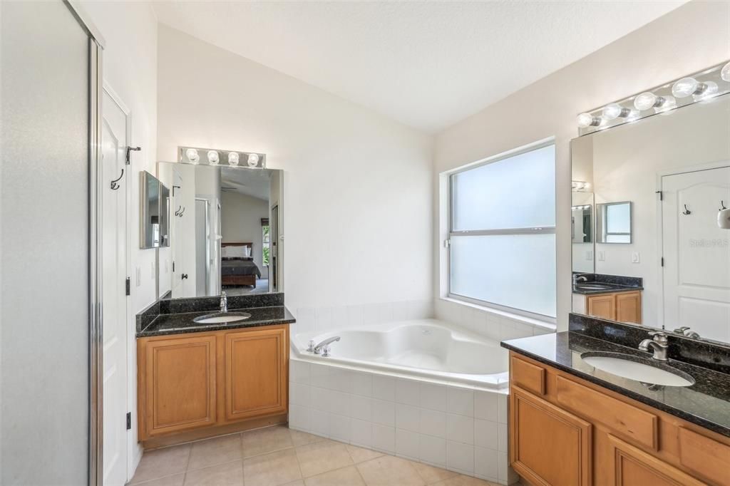 Double Vanity in Primary Bathroom with Garden Tub and Separate Shower and vaulted ceilings
