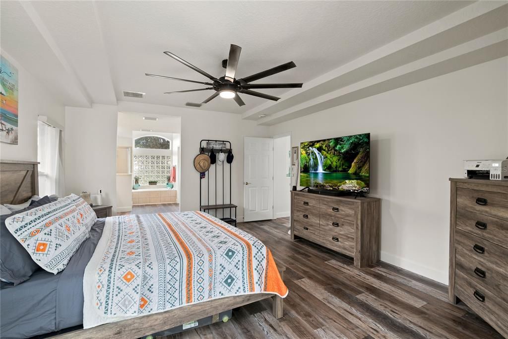 Spacious master suite with tray ceiling and slider doors leading to pool and patio