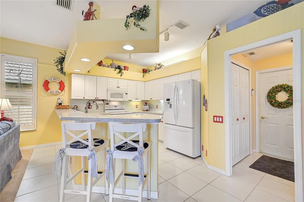 Kitchen looking into adjacent laundry room with double door pantry to the left and door to garage straight ahead.