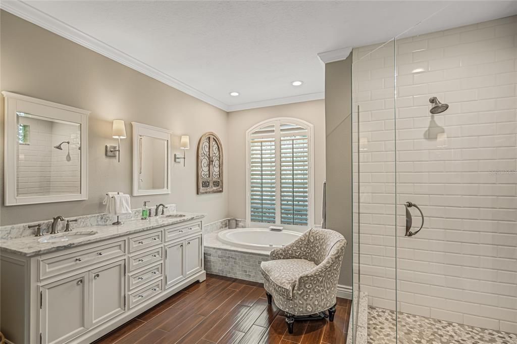 Primary bathroom with seamless shower door, stone floor and marble tops